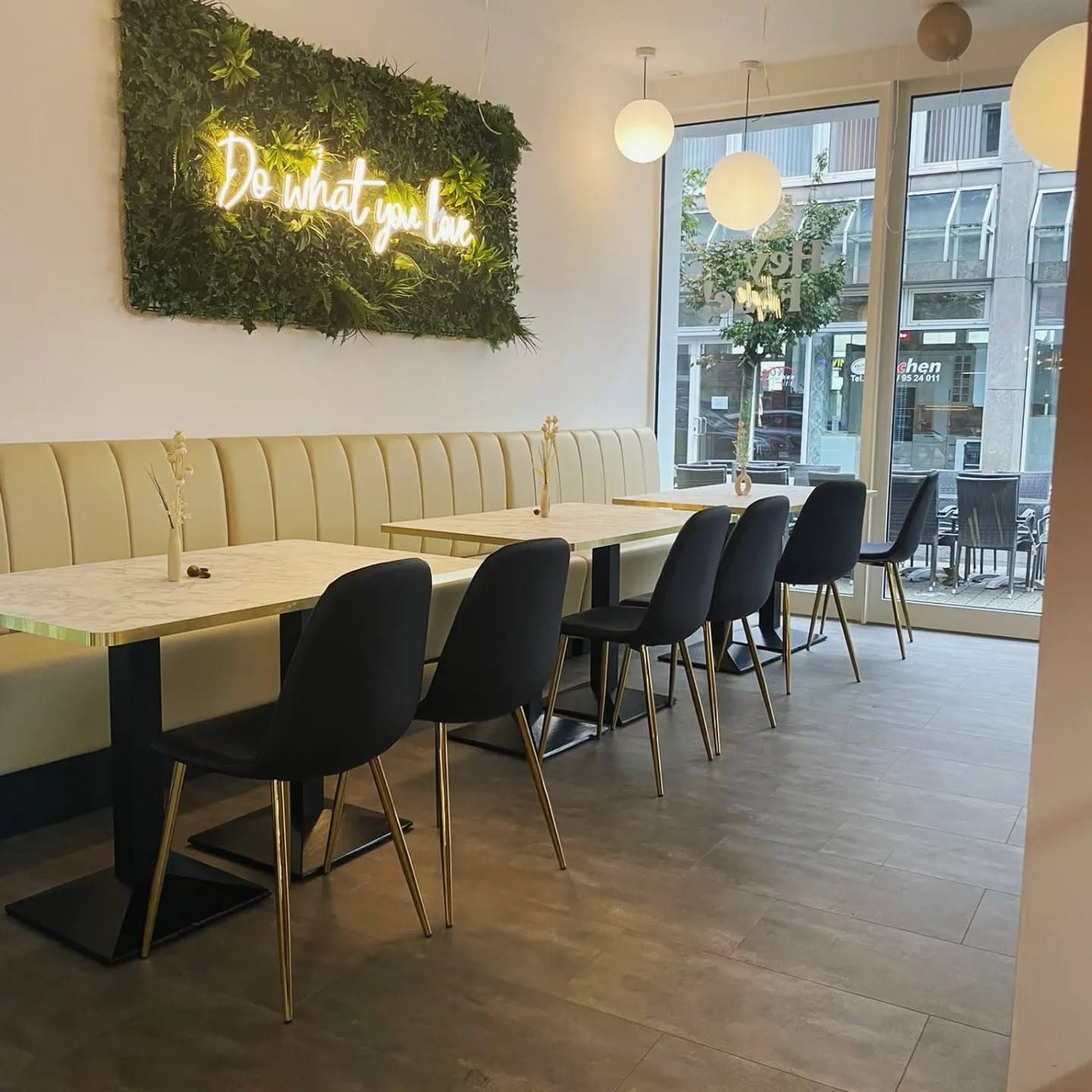 Heller Sitzbereich mit Neon-Schriftzug "Do what you love" und Mooswand im Hey Fede! Wetzlar
